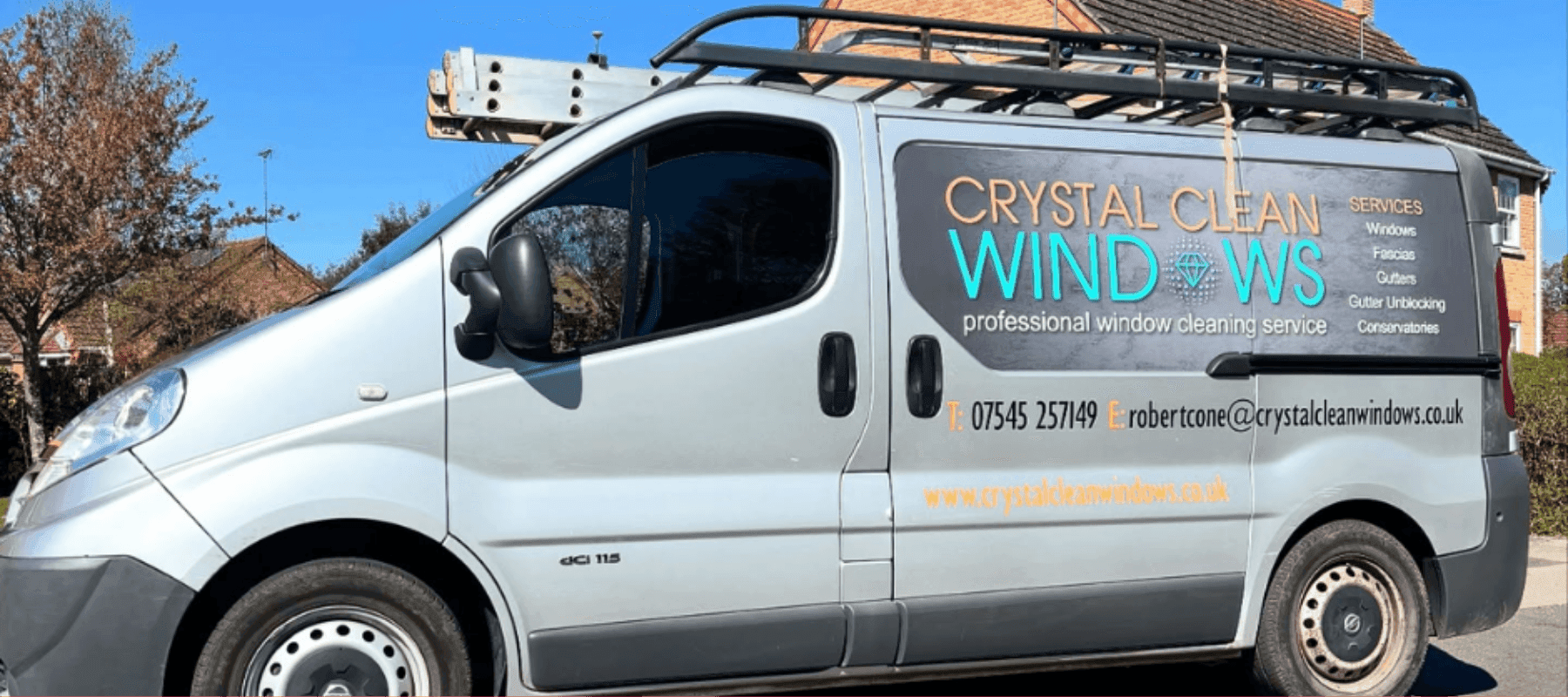 A branded window cleaning van parked in front of a house
